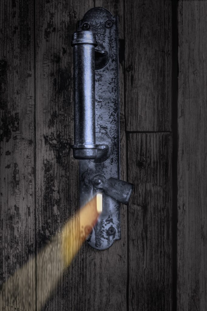 A stream of light coming through the keyhole of an old wooden door